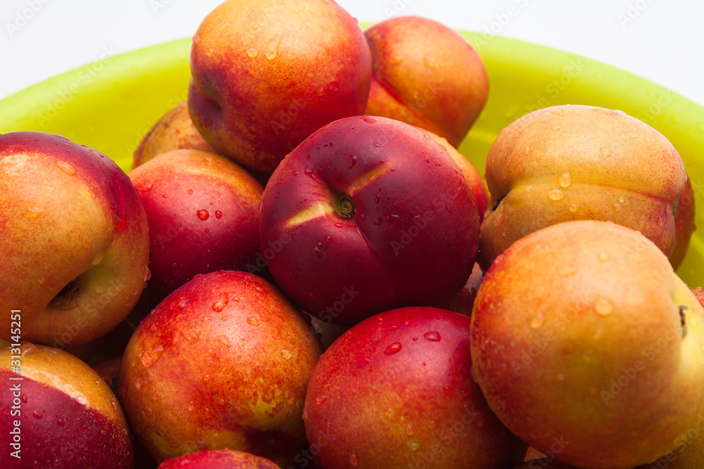 Ripe peaches in a green basket on a white Ripe peaches in a green basket on a white