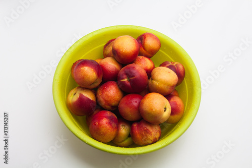 Ripe peaches in a green basket on a white