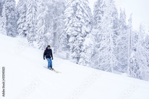 Young man in ski suit skiing downhill in mountains during winter vacation