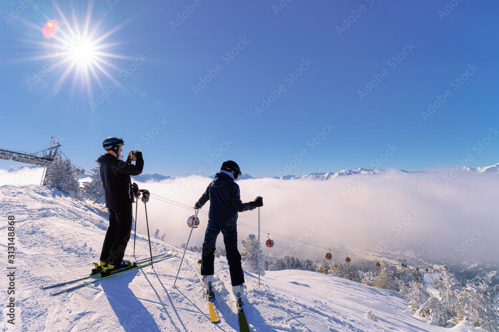People Skiers skiing and taking photos in Zillertal Arena ski resort in Tyrol in Mayrhofen in Austria in winter Alps. Ski in Alpine mountains with white snow and blue sky. Snowy slopes. Sun shining.