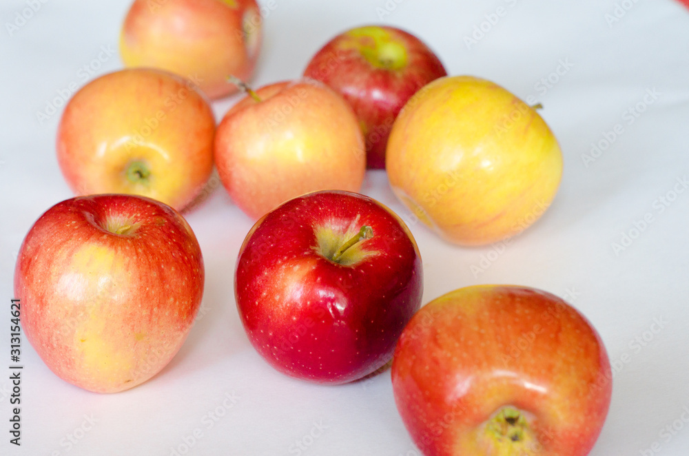 A few fresh red and yellow apples lie on a white background. Selective focus. Close up. A few fresh red and yellow apples lie on a white background. Selective focus. Close up.