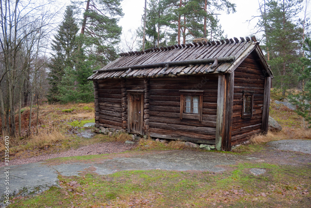 An ancient authentic 18th century wooden house in an autumn forest on the island of Seurasaari in Helsinki, Finland, a cloudy day in late autumn. The harsh beauty of ancient Finland An ancient authentic 18th century wooden house in an autumn forest on the island of Seurasaari in Helsinki, Finland, a cloudy day in late autumn. The harsh beauty of ancient Finland