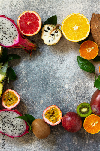 Exotic asia fruit background. Assorted ripe juicy tropical summer seasonal fruits on a gray stone background. Top view flat lay background. Copy space.