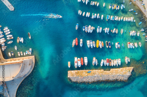 Aerial view of colorful boats and yachts in port in blue sea at sunset. Summer landscape with beautiful motorboats in harbor, pier, transparent water in Dubrovnik. View from above of harbour. Travel