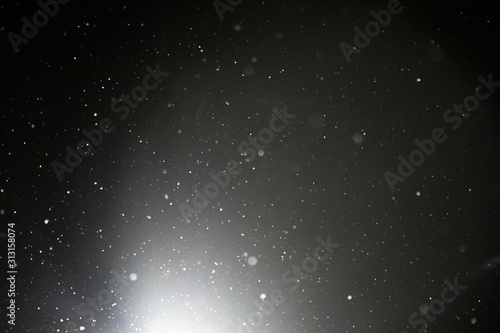 Snow and bokeh in the light of a lantern on a black background