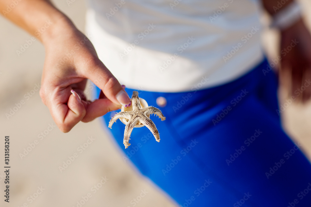 Girl's hand holds a starfish on a blue background