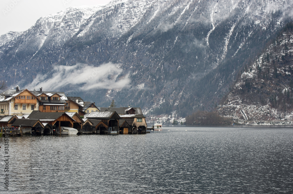 View of cottages of Hallstatt down the foggy mountains with snow on the trees in winter