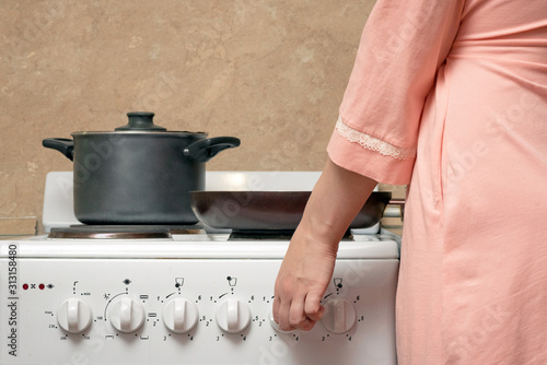 Woman is cooking food on the electric stove on home kitchen.