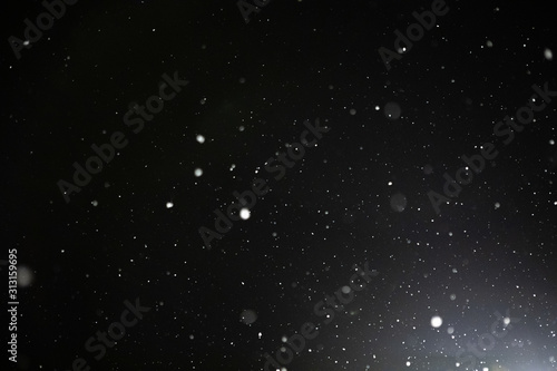Snow and bokeh in the light of a lantern on a black background