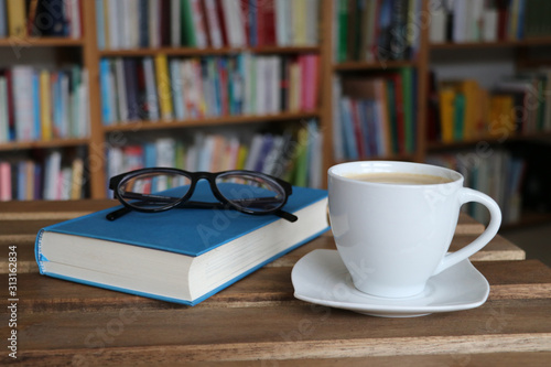 Kaffee, Cappuccino, Tasse, Buch mit Brille vor Bücherregal