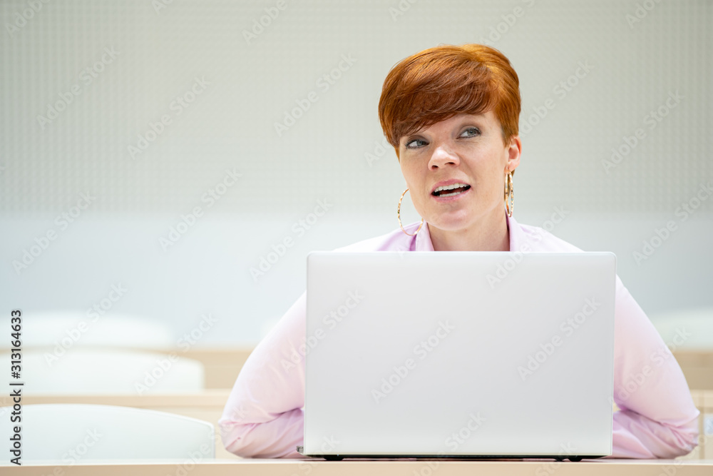 student in high school auditorium at school with white laptop student in high school auditorium at school with white laptop