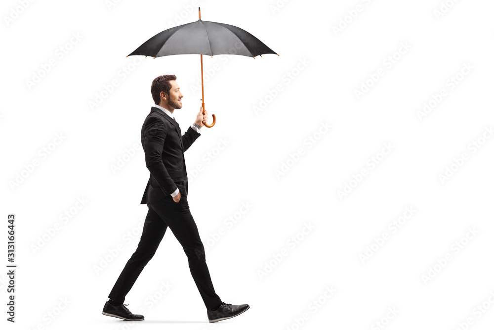 Handsome businessman walking with an open umbrella