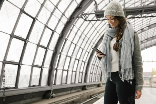 Wallpaper Mural Happy young woman using smartphone at the station platform Torontodigital.ca