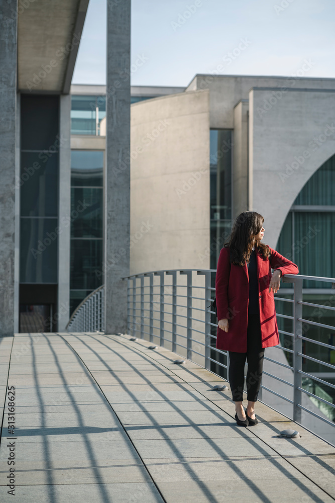 Modern businesswoman standing on a bridge and looking sideways Modern businesswoman standing on a bridge and looking sideways