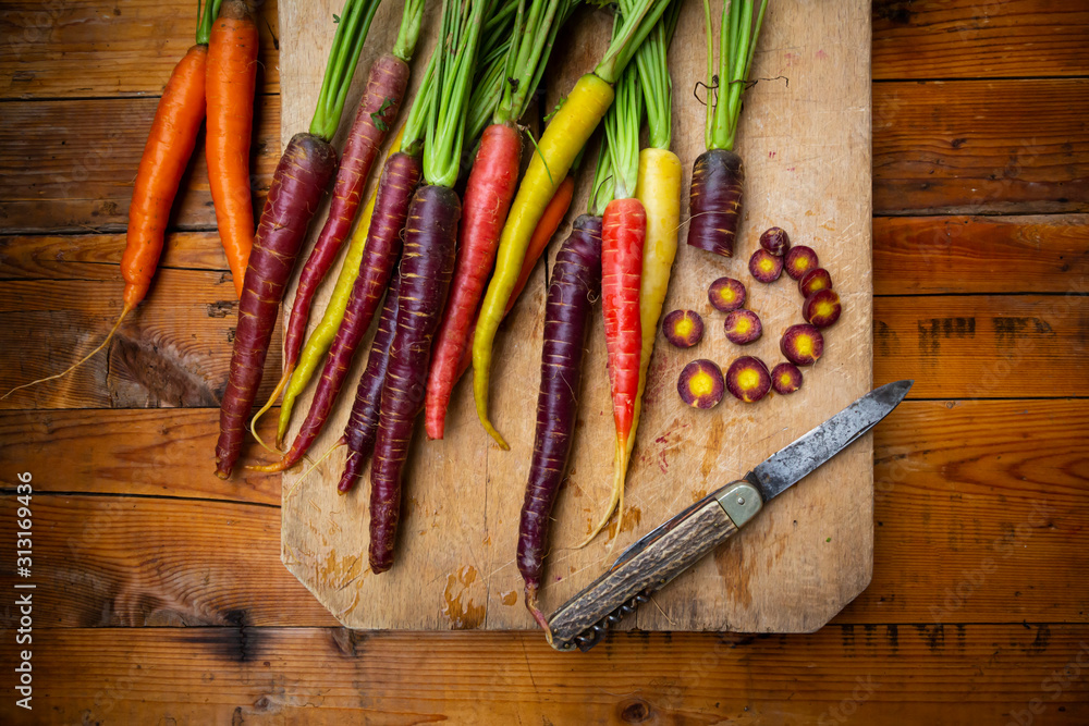 Penknife and fresh colorful carrots lying on cutting board Penknife and fresh colorful carrots lying on cutting board