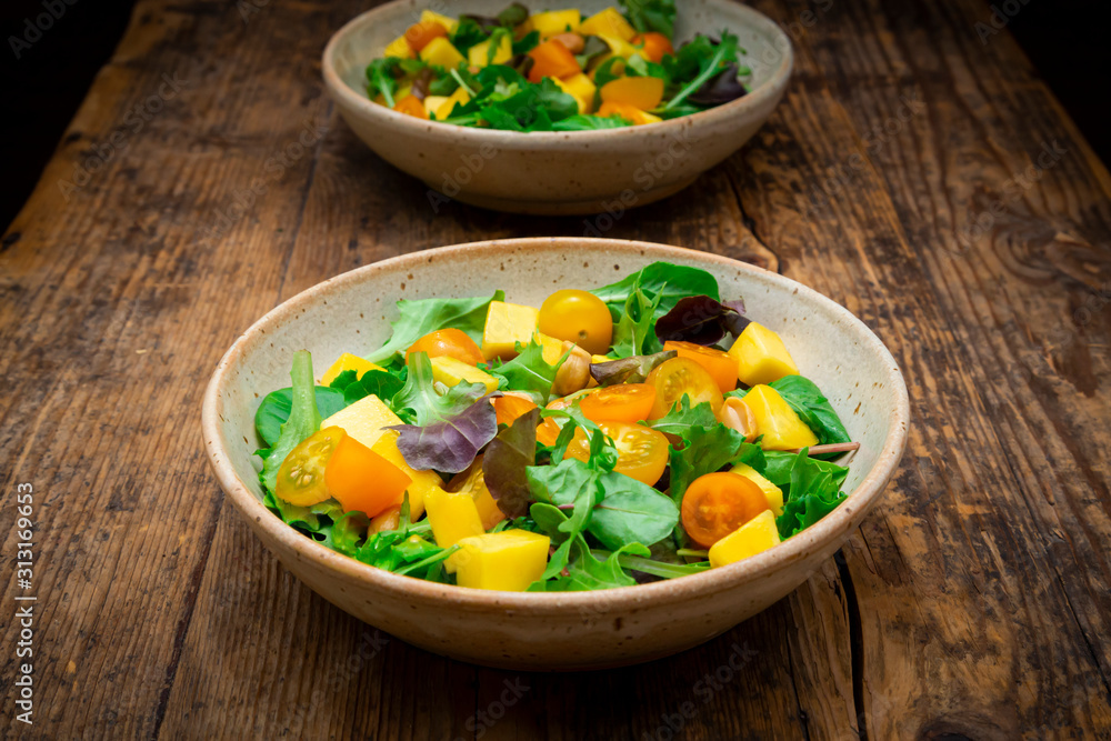 Bowls of salad with spinach, mango fruit, arugula and roasted peanuts Bowls of salad with spinach, mango fruit, arugula and roasted peanuts