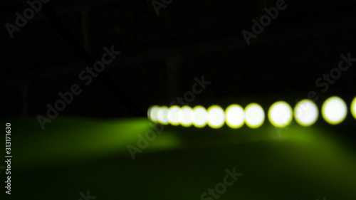 Yellow LED bokeh strip on a black and green background. © ksenikin