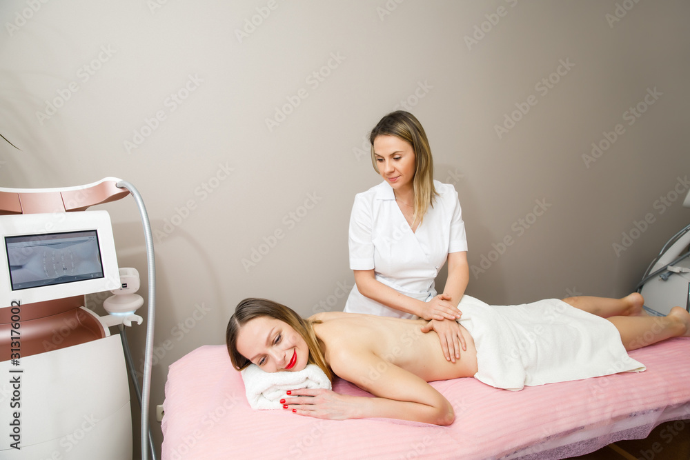Obraz premium Massage and body care. Male doctor does massage to a young girl in spa salon