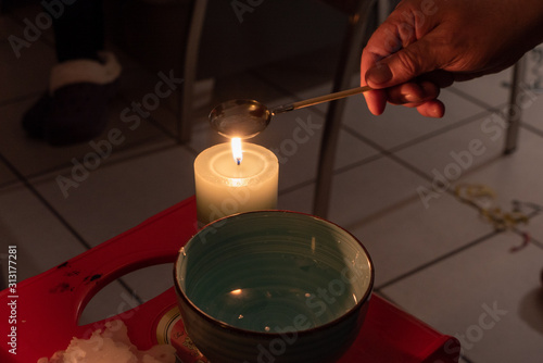 Wallpaper Mural Hand beim Wachsgießen mit Kerze, Löffel und Schale mit Wasser Torontodigital.ca