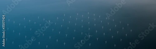 Windmills at the sea. Clean energy made by the wind. Photo in bird perspective. Offshore wind farm. photo
