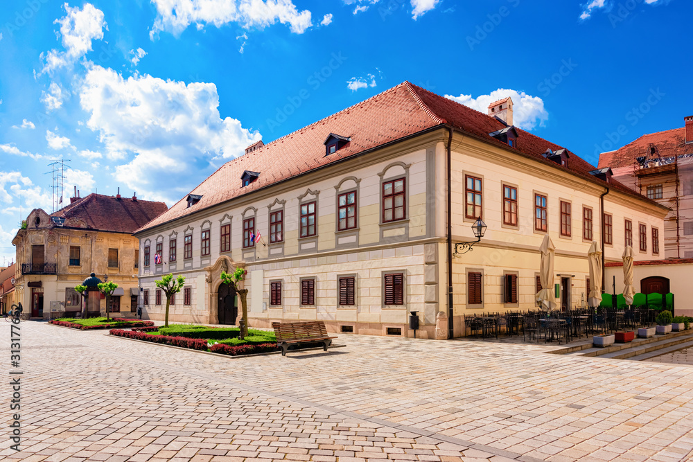Street with Herzer palace with flags in Old city of Varazdin in Croatia. Panorama and Cityscape of famous Croatian town in Europe in summer. Travel and tourism for tourists.