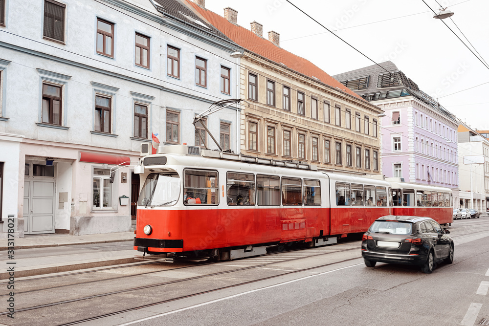 Typical red tram on road in Mariahilfer Strasse in Innere Stadt in Old city center in Vienna in Austria. Public transport and Street archtecture in Wien in Europe. Cityscape view. Building landmark.