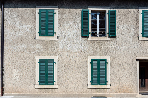 Facade of a stone house with green shutters. Swiss - French border © ako-photography