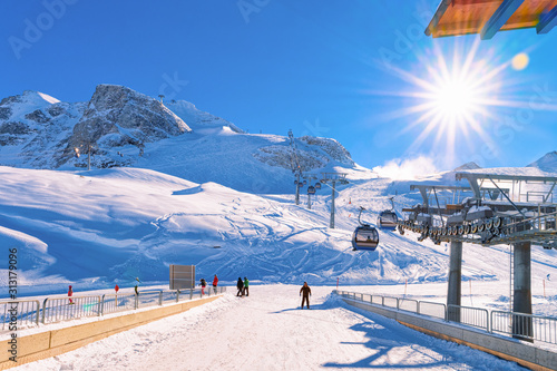 Cable cars and skiers skiing at Hintertux Glacier in Tyrol in Mayrhofen in Zillertal valley in Austria in winter Alps. Chair lifts and people on ski in Hintertuxer Gletscher in mountains. Sun shining photo