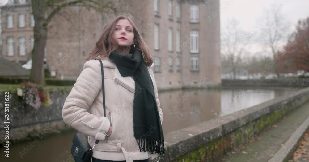 Beautiful young blond woman waiting for someone. Medium close shot of her. She is wearing a white warm coat made of fake fur, red lipstick on. Winter holidays, Flers's castle, Normandy. Beautiful young blond woman waiting for someone. Medium close shot of her. She is wearing a white warm coat made of fake fur, red lipstick on. Winter holidays, Flers's castle, Normandy.