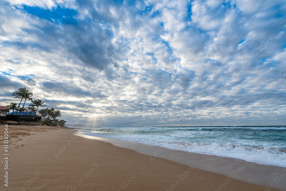 Obraz premium Rays of sunlight shining through a vast sunset sky over Sunset Beach on the north shore of Oahu, Hawaii, USA