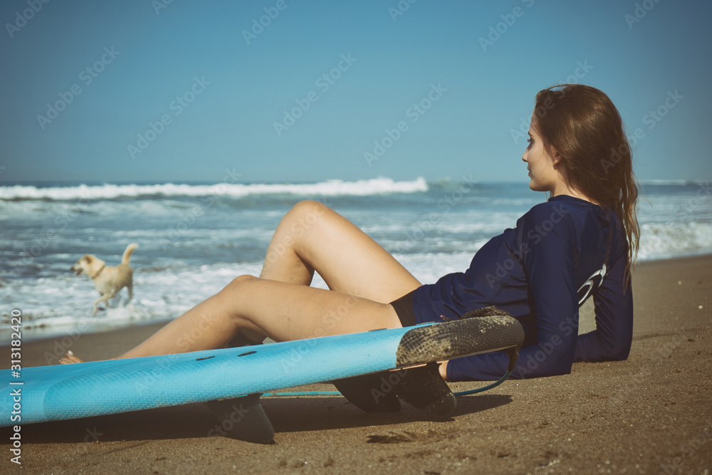 Female model with long hear style and beach wear with surfboard at sunny morning at the Balinese ocean beach