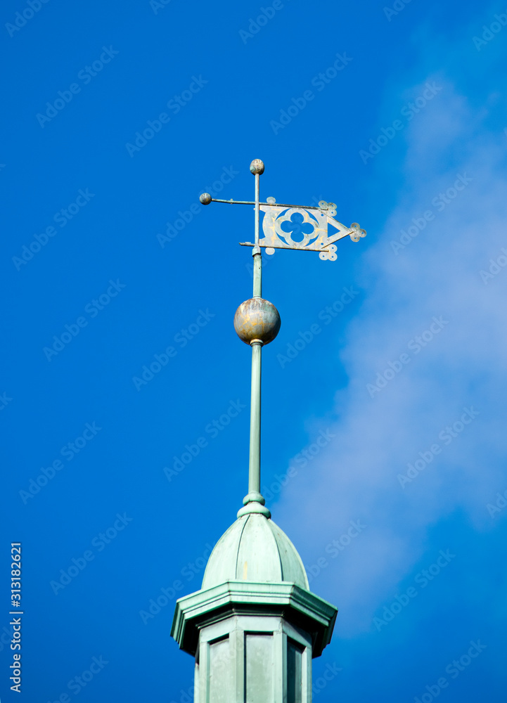 A WEATHER VANE with directional points, located on a spire of a buildings tower