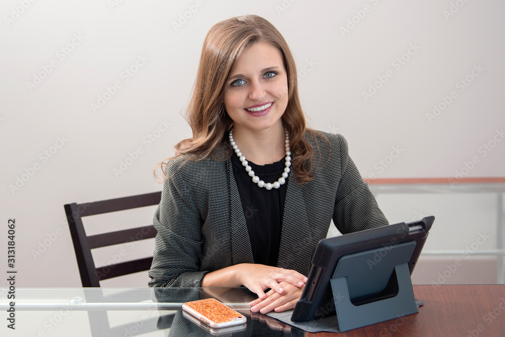Young professional woman shown in her office - with tablet computer and mobile phone on desk Young professional woman shown in her office - with tablet computer and mobile phone on desk