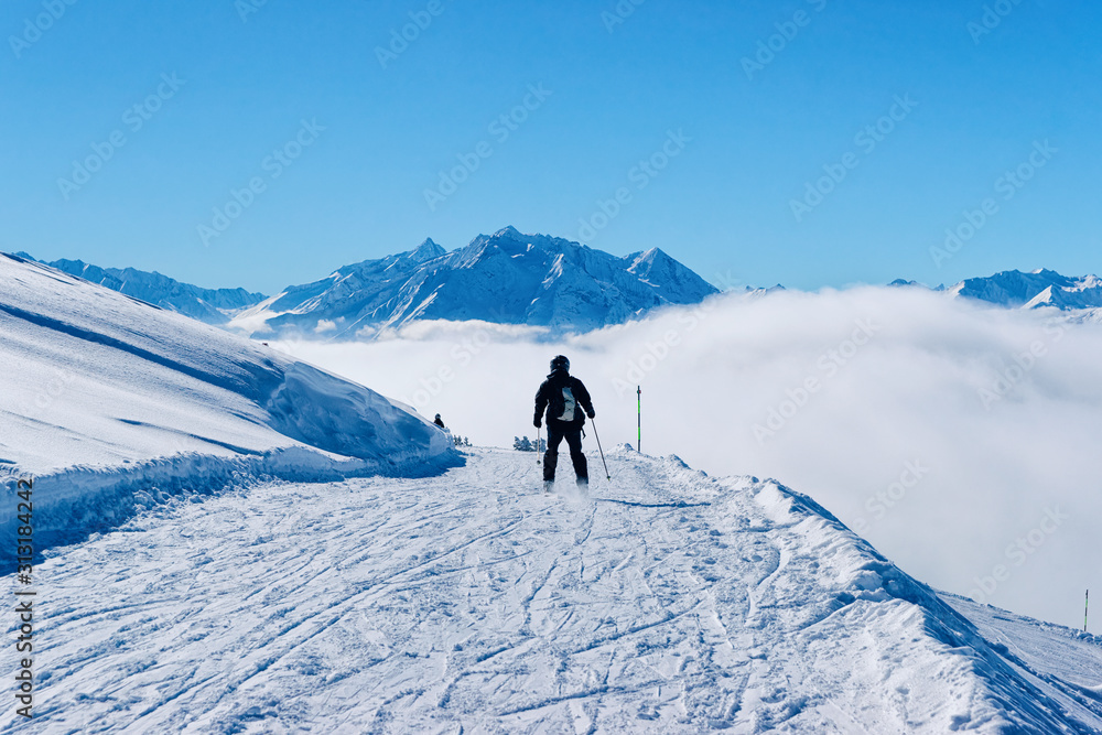 Man Skier skiing in Zillertal Arena ski resort in Tyrol in Mayrhofen in Austria in winter Alps. Alpine mountains with white snow and blue sky. Downhill fun at Austrian snowy slopes.