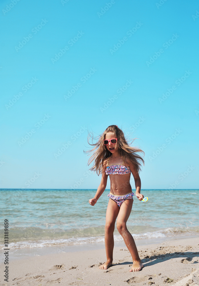 Cute little girl has fun on the beach. Summertime concept. Cute little girl has fun on the beach. Summertime concept.