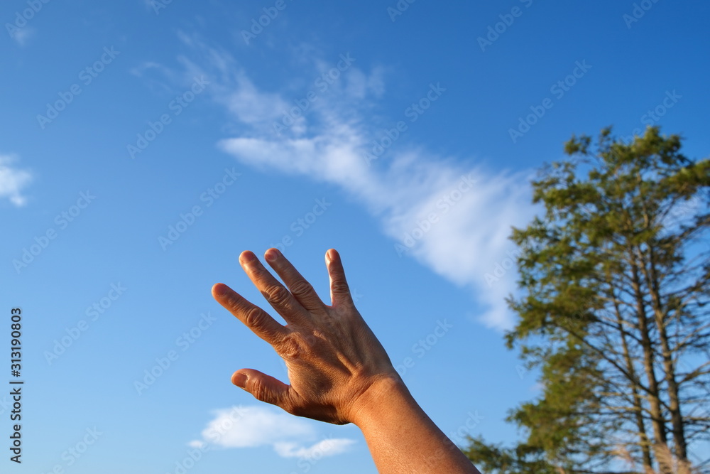 Hand of person waving to a hand shape Cirrus type cloud in the sky. Hand of person waving to a hand shape Cirrus type cloud in the sky.