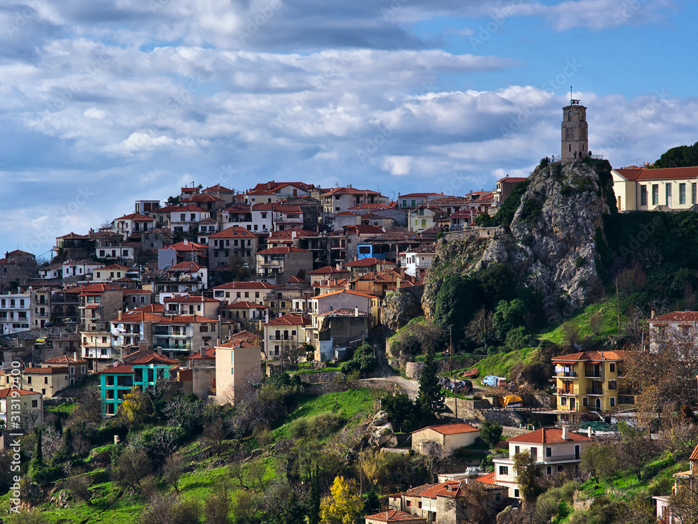 View to Arachova village, Greece with iconic tower clock, under cloudy sky.