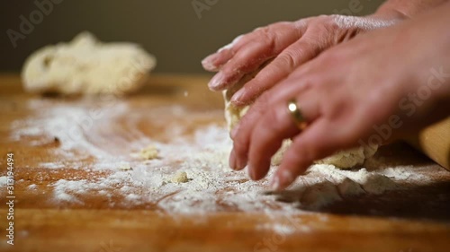 Slow motion clip of female hands kneading pie dough on floured surface. photo