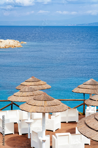 Street cafe with tables and chairs in Capo Testa in Santa Teresa Gallura province in Sardinia, Italy. Restaurant with porch and umbrellas in Sardegna. photo