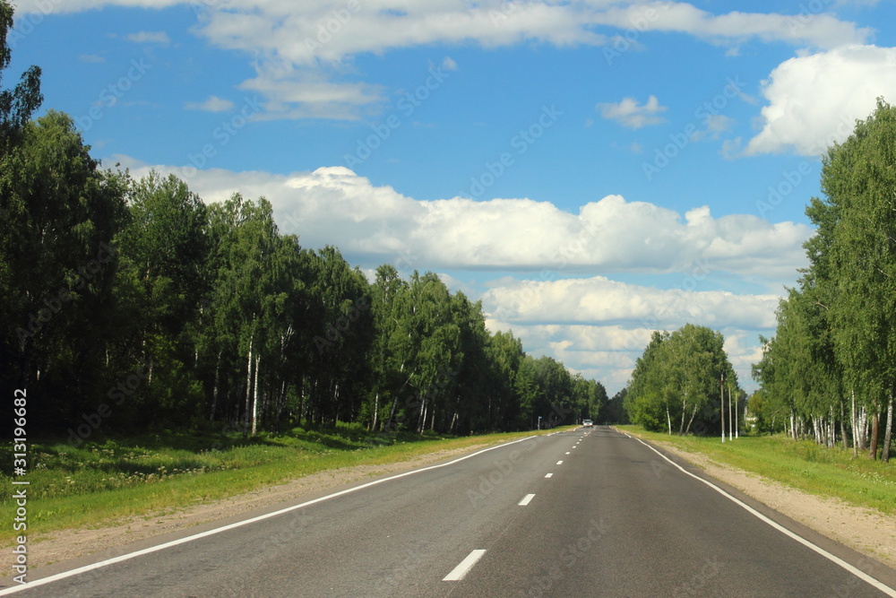 Beautiful Summer empty highway landscape, endless road on Sunny day on trees and cloudy blue sky background