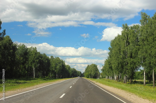 Summer empty road landscape, endless highway on Sunny day on trees and blue sky with clouds background