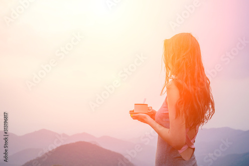girl drinking cup of hot tea on top mountain in india herb plantation