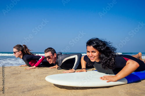 Canvas Print surf instructor and two girls beginner surfers try to stand up on surfboard on l