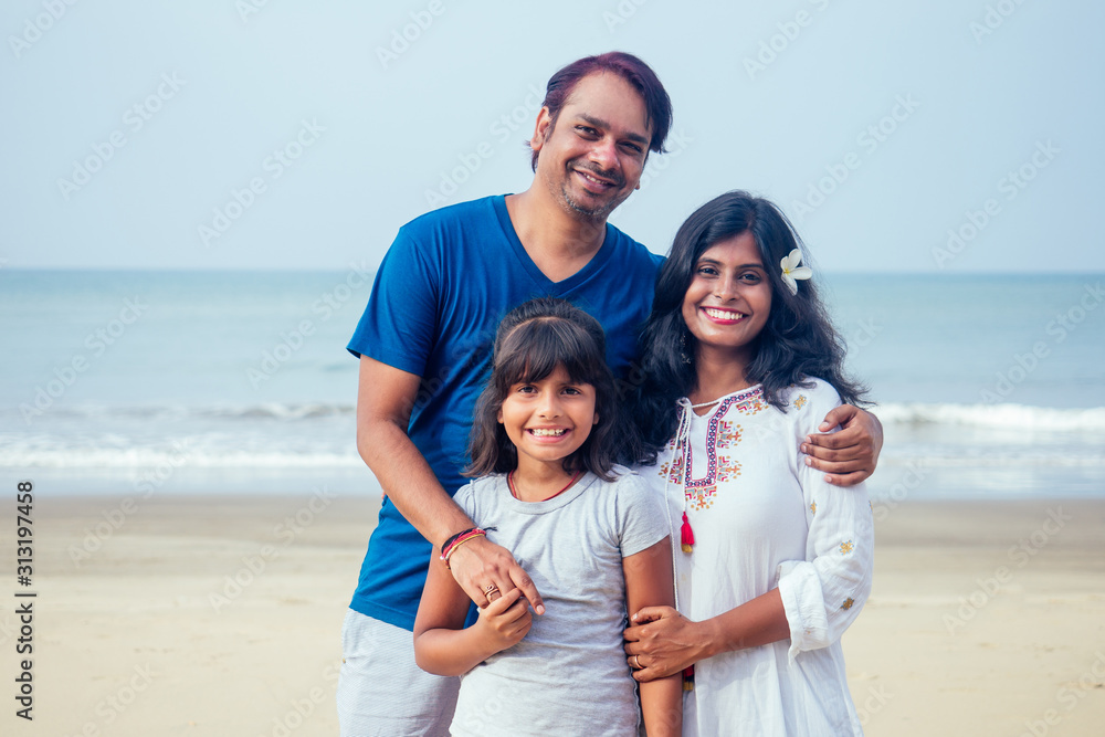 Young indian family relaxing at the beach on beautiful summer day in Goa