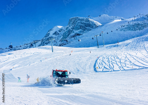 Men Skiers and snowboarders on Hintertux Glacier in Tyrol in Mayrhofen, winter Alps. People with Ski and snowboard at Hintertuxer Gletscher in Alpine mountains. Snowcat ratrack working