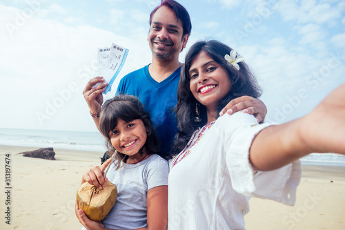 Canvas Print Young indian family relaxing and taking selfie on camera smartphone with ticket