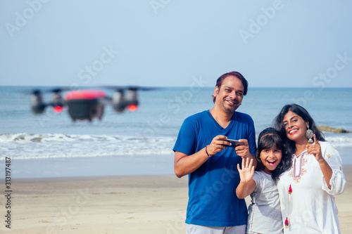 happy indian family are operating the drone by remote control in the beach in Goa
