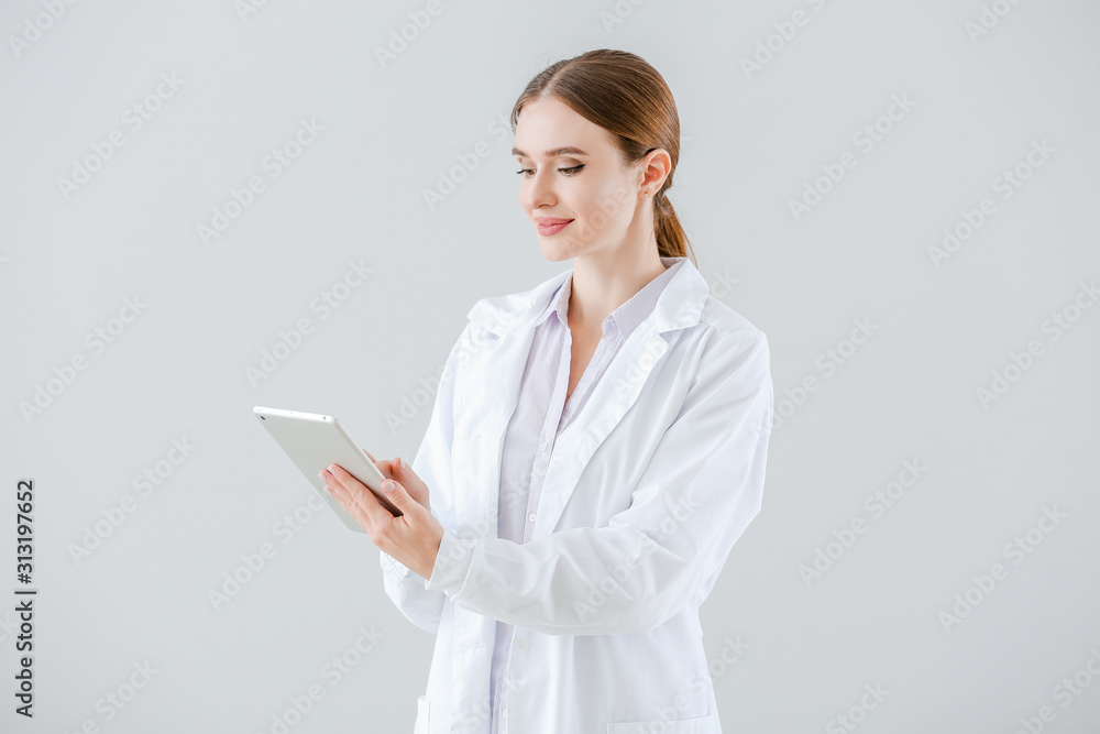 Portrait of female doctor with tablet computer on light background Portrait of female doctor with tablet computer on light background
