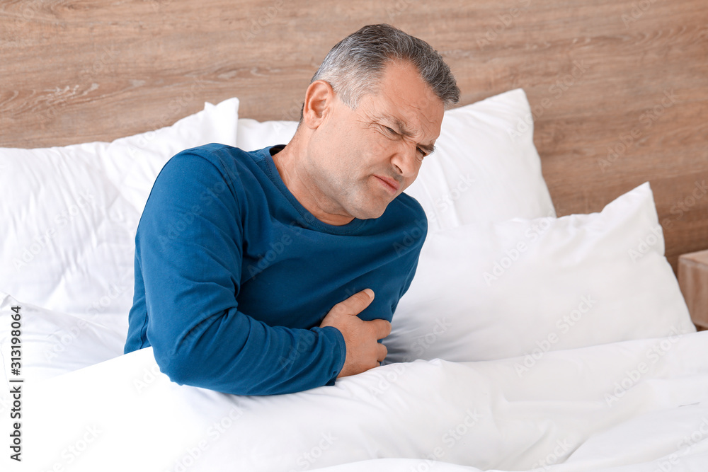 Mature man suffering from heart attack in bedroom Mature man suffering from heart attack in bedroom