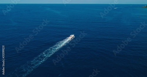 Aerial following, rotating over trolling island fishing boat, Roatan